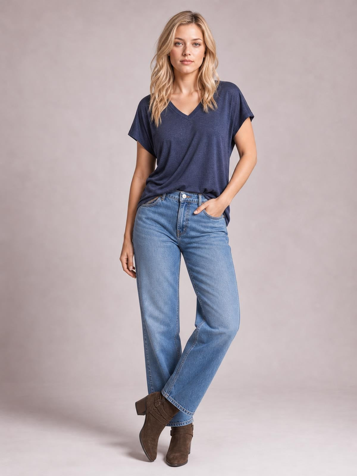 Model poses in a navy V-neck short sleeve T-shirt with a relaxed straight silhouette, paired with jeans and one hand in her pocket.