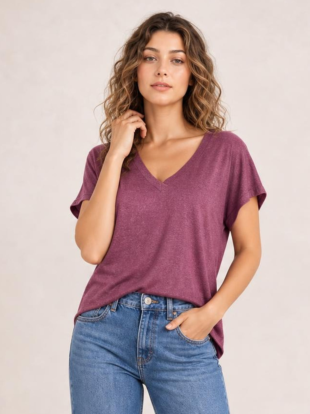 Model poses in a plum V-neck short sleeve T-shirt with a relaxed, slightly loose silhouette and simple construction.