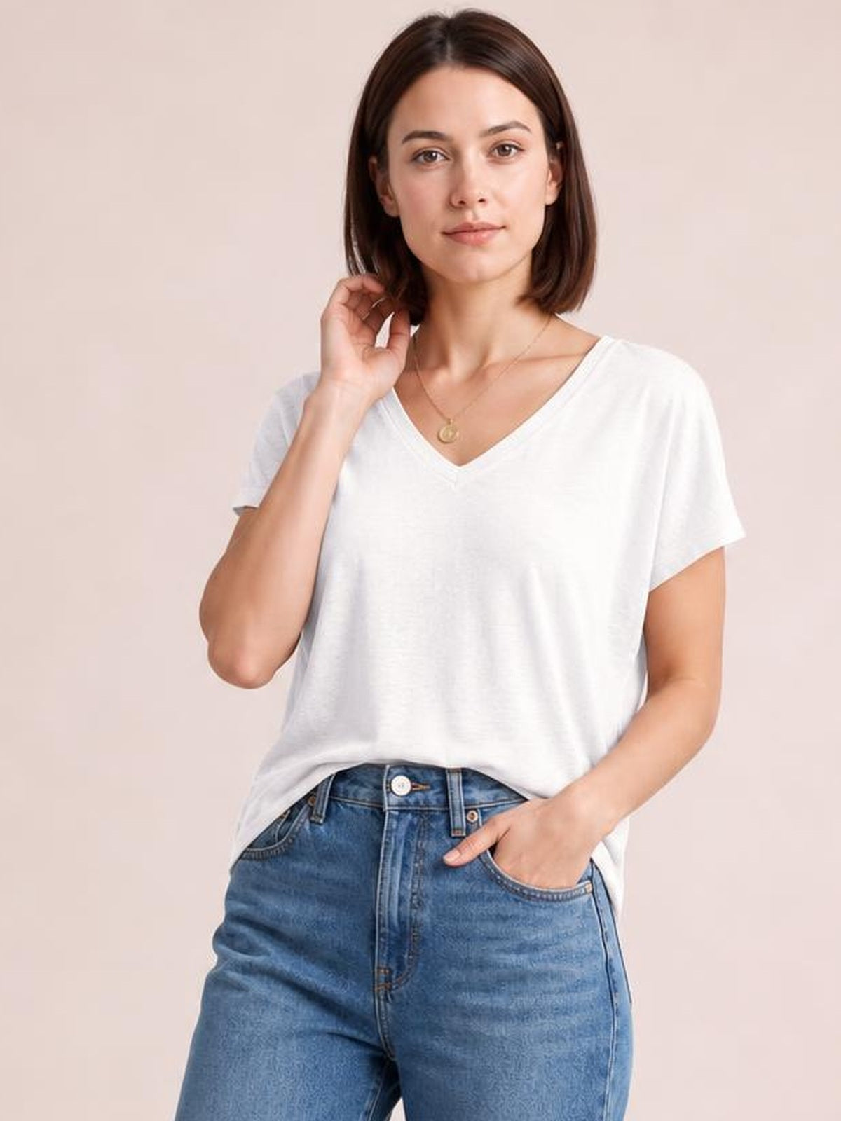 Model wears a white V-neck short sleeve T-shirt with a relaxed straight silhouette, softly draped construction, and a slightly stretchy opaque finish.