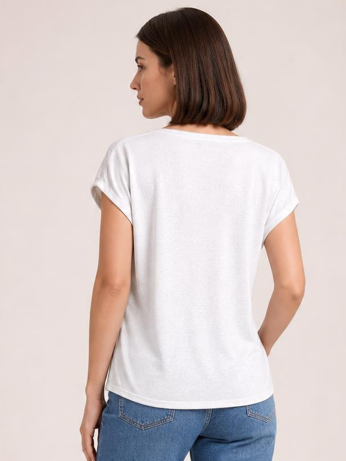 Model shown from behind wears a white short sleeve T-shirt with a relaxed straight silhouette, cuffed sleeves, and a gently curved hem while looking over her shoulder.