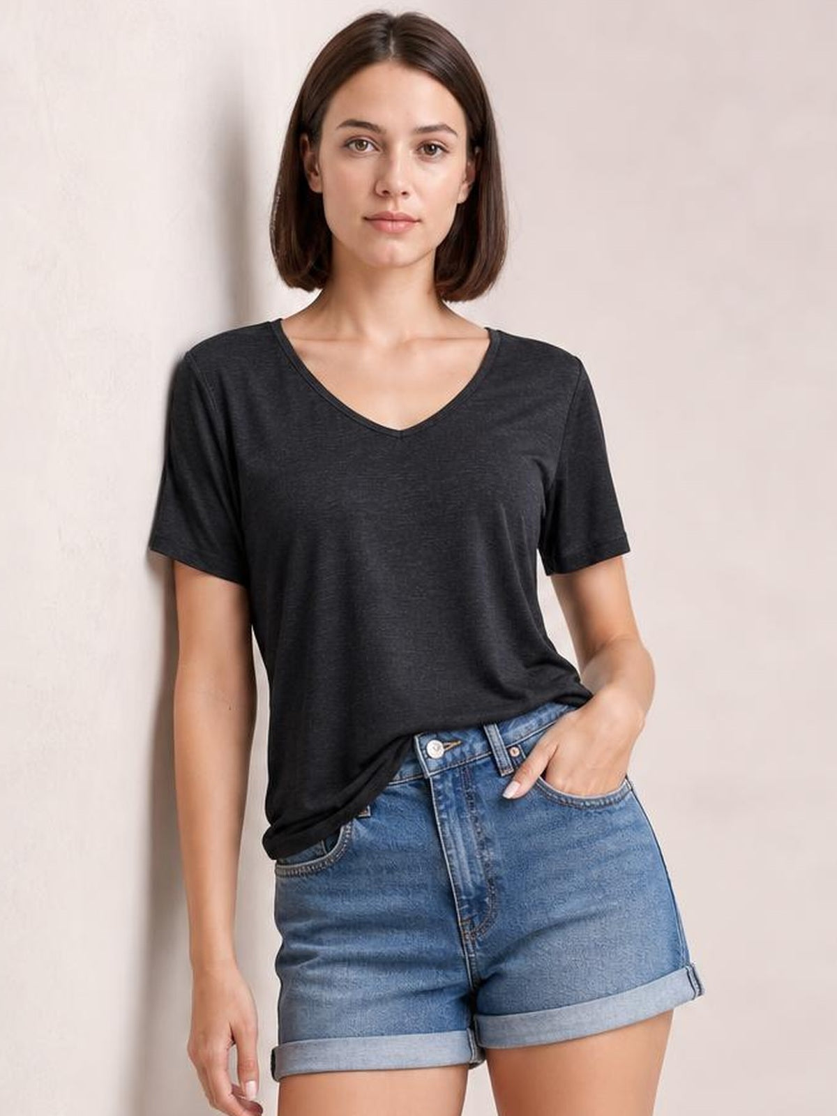 Model wearing a charcoal V-neck short sleeve T-shirt with a relaxed straight silhouette and clean neckline, paired with cuffed denim shorts.