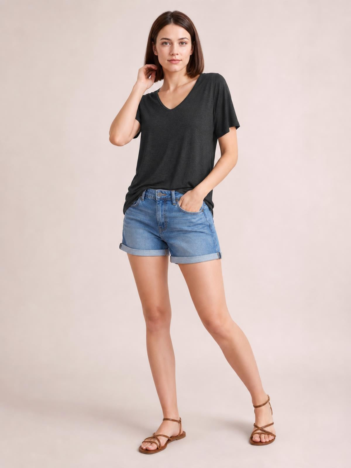 Model poses in a charcoal V-neck short sleeve T-shirt with a relaxed silhouette and slightly draped construction.