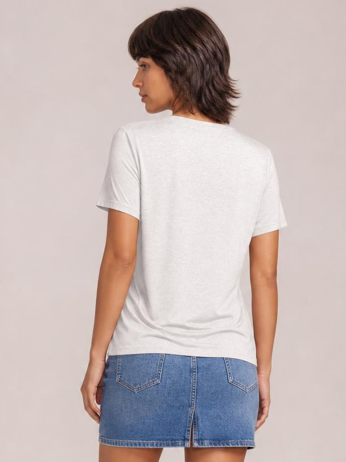 A model looks over her shoulder wearing a white short sleeve T-shirt with a relaxed silhouette, smooth construction, and straight hem.