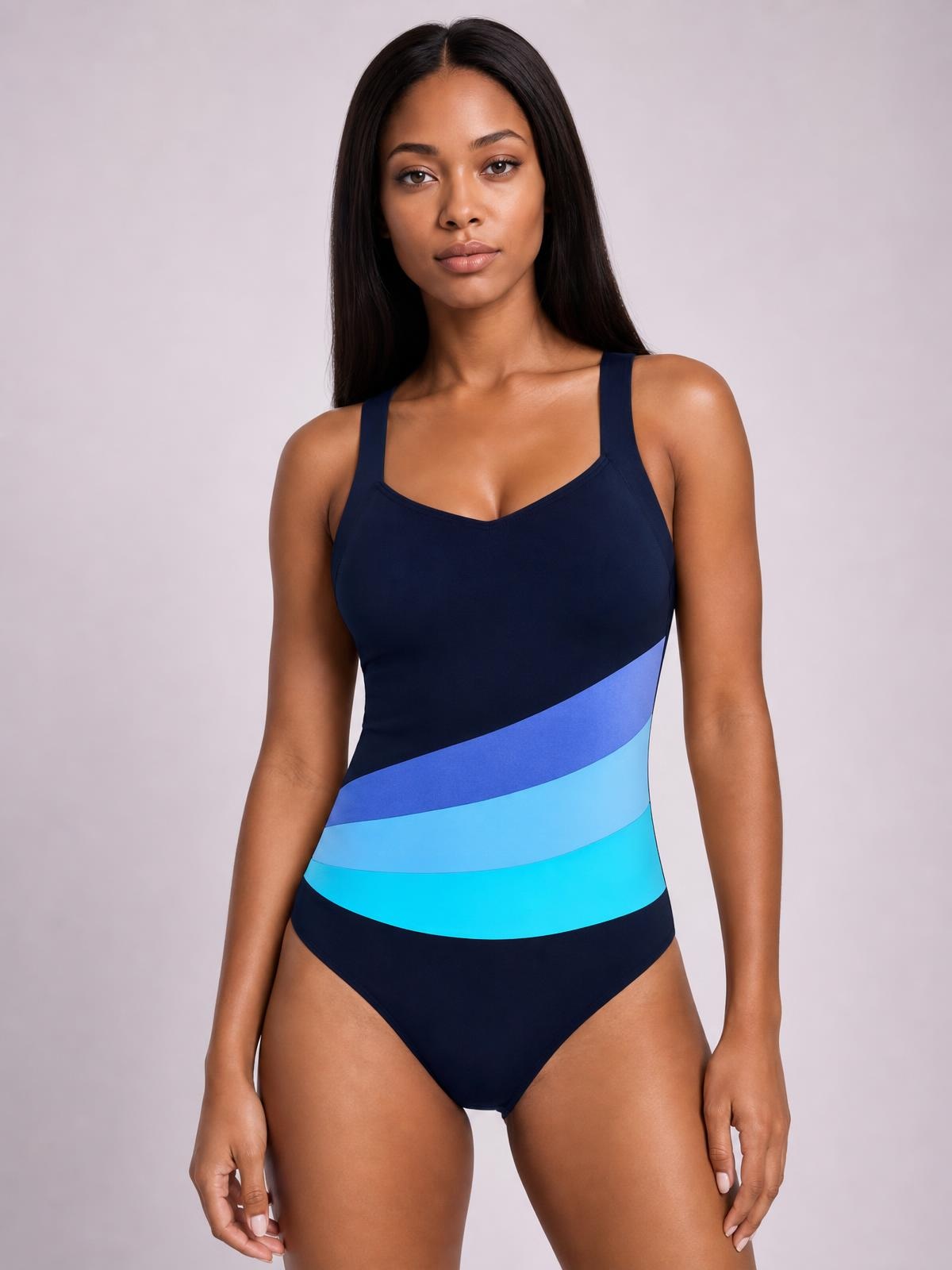 Model stands facing forward in a navy sleeveless V-neck one-piece swimsuit with a fitted silhouette and curved blue printed stripes.