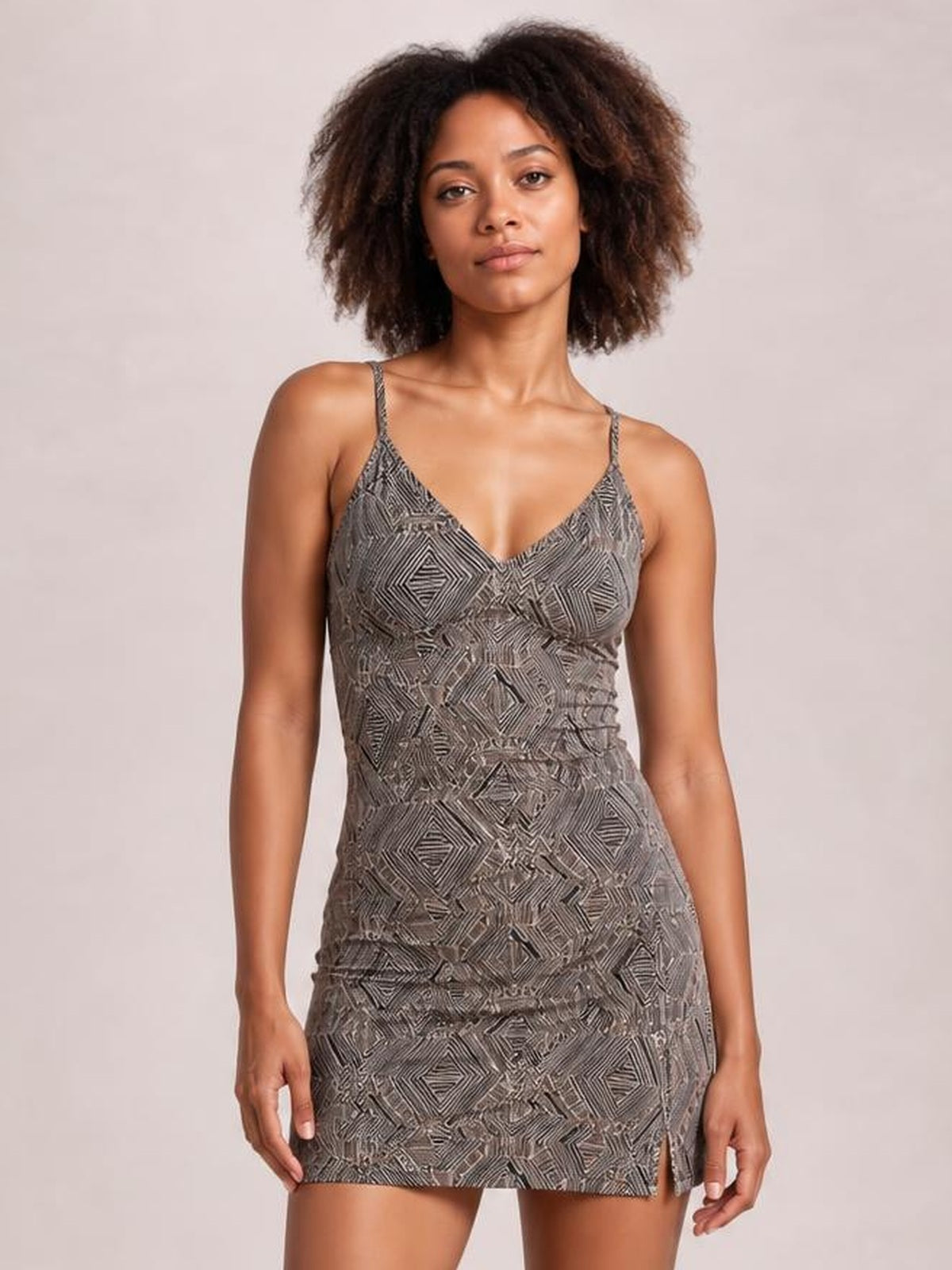 A model stands in a gray geometric-print V-neck spaghetti strap tankini with a fitted swim top and matching skirt silhouette with a side slit.