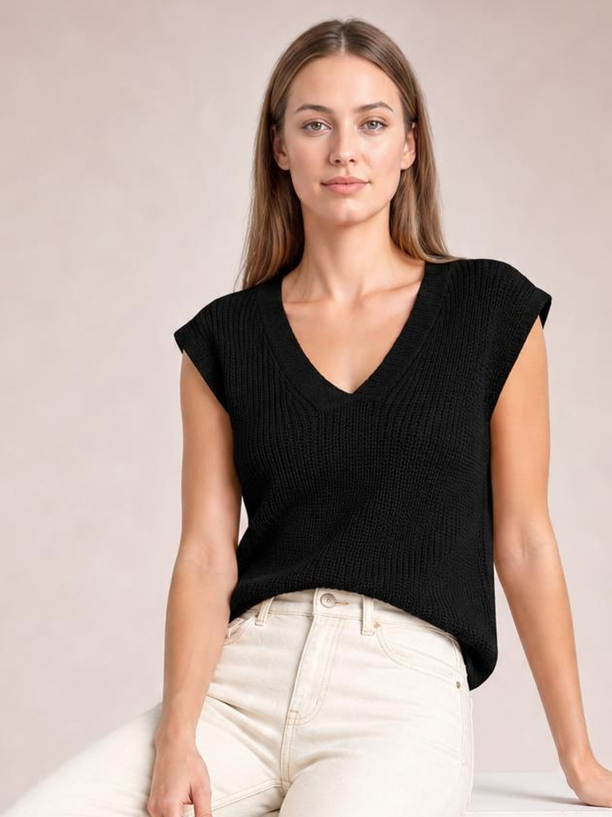 Model wearing a black ribbed V-neck sweater vest with a relaxed silhouette, wide shoulders, sleeveless construction, and a straight hem.