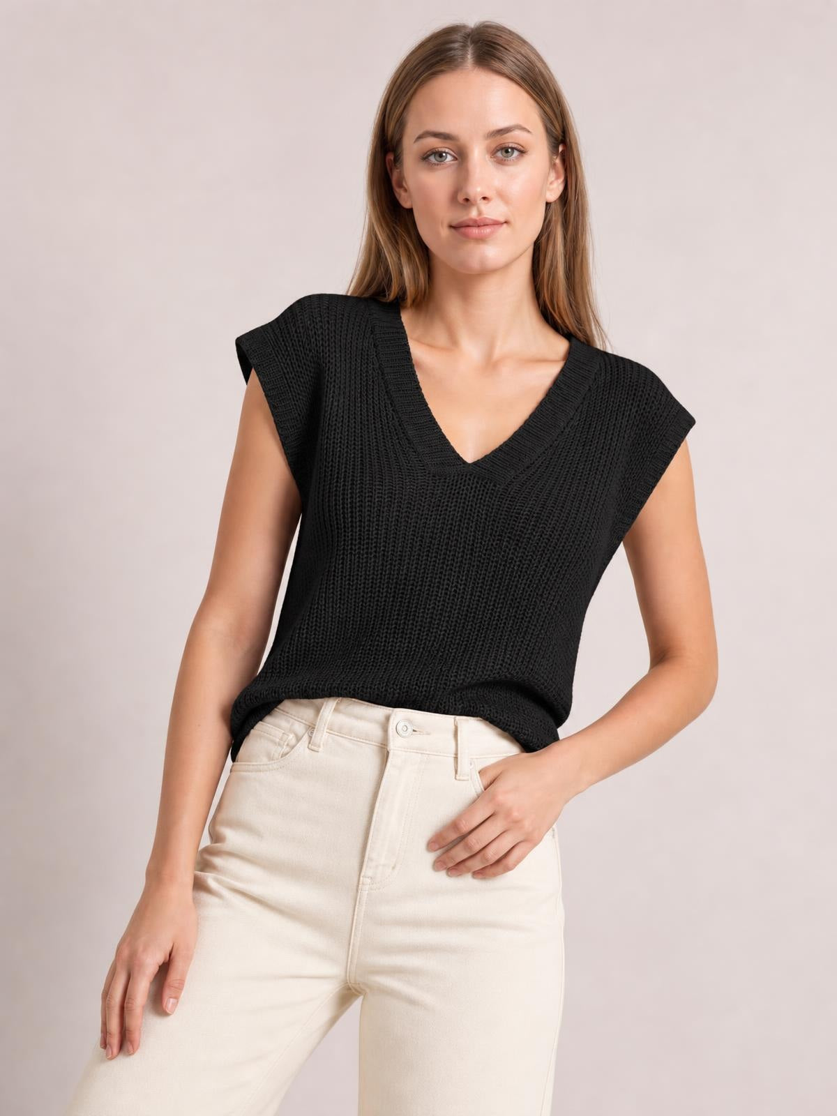 Model wearing a black V-neck sweater vest with a textured knit, sleeveless cut, ribbed neckline and hem, and a relaxed straight silhouette.