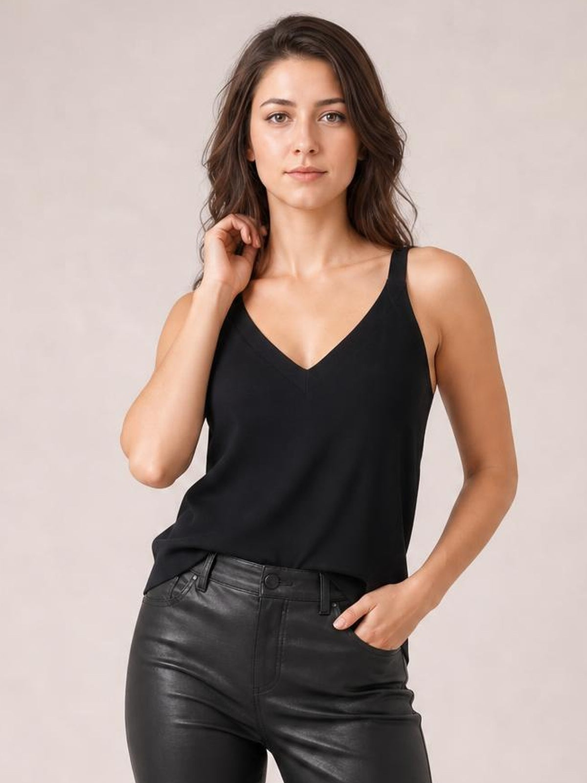 Model poses in a black V-neck wide strap cami with a relaxed straight silhouette and simple construction.