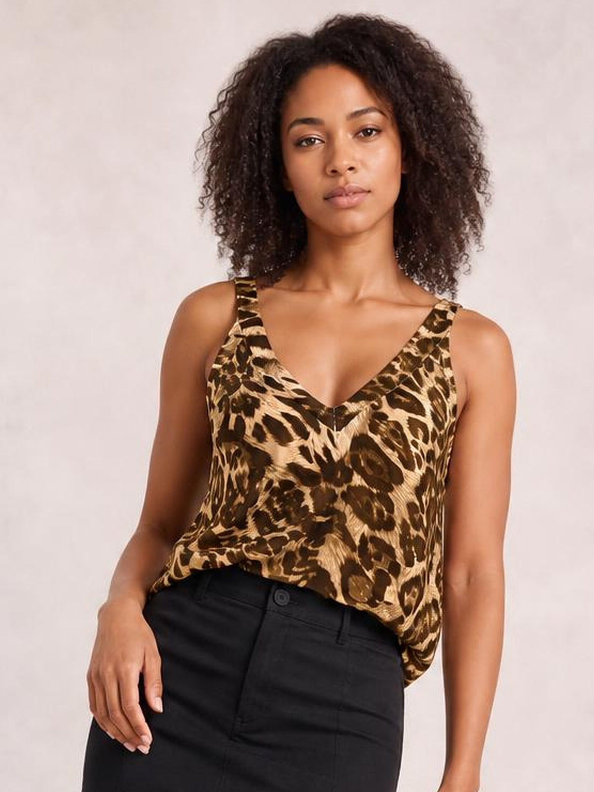 Model wears a brown and black leopard-print V-neck wide strap cami with a relaxed silhouette, posing with one hand resting near her hip.
