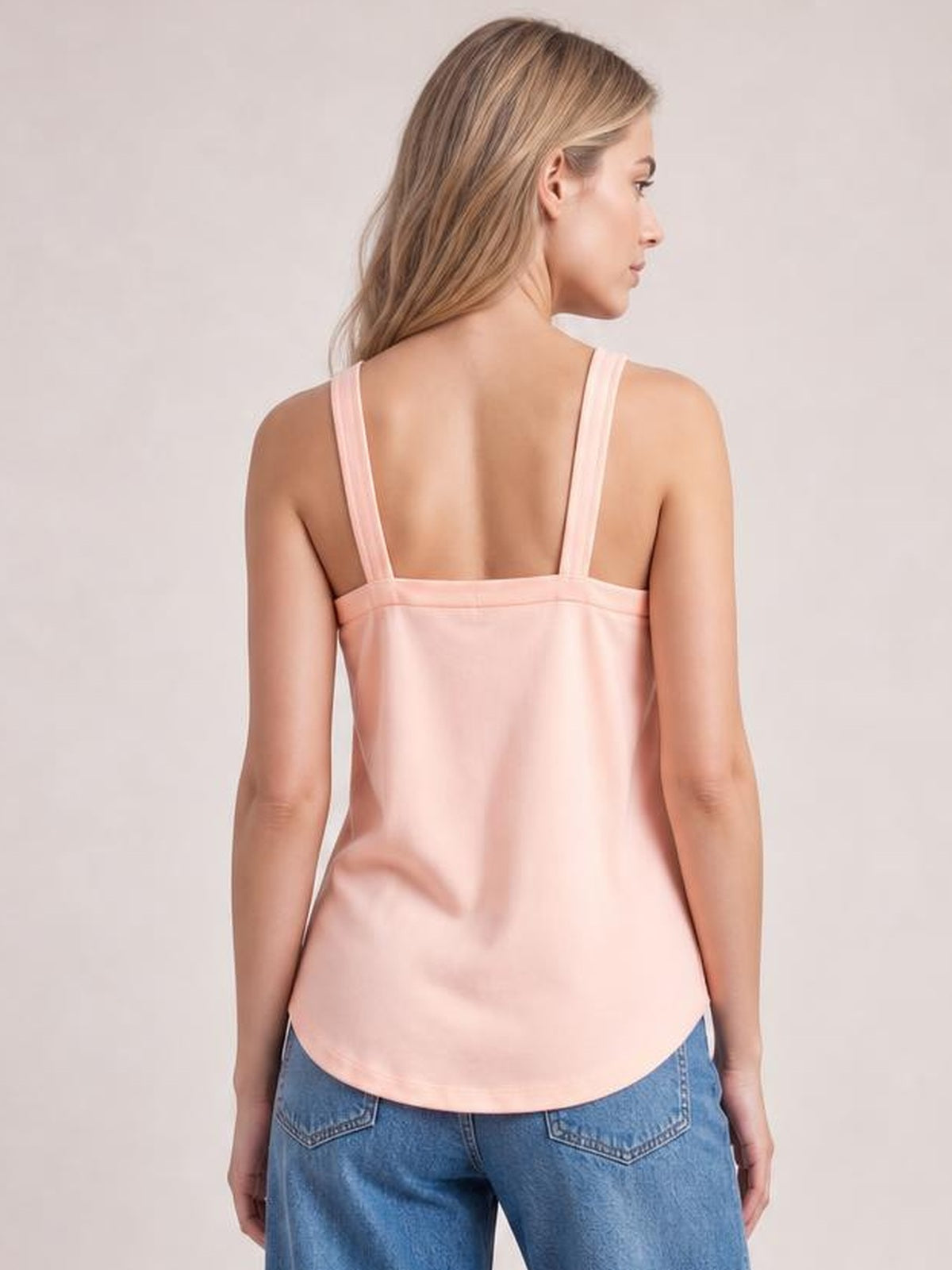 Model shown from the back in a pale pink V-neck cami with wide straps, a relaxed straight silhouette, and curved hem.