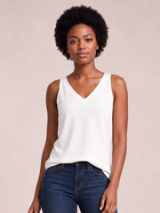 Model wears a white V-neck wide strap cami with a relaxed straight silhouette, slightly stretchy opaque fabric, and a softly curved hem.