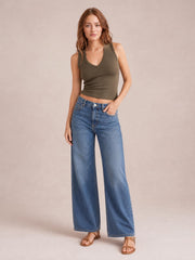 A model stands with one hand in her jeans pocket wearing an olive V-neck wide strap tank with a fitted, ribbed silhouette and double-stitched neckline.