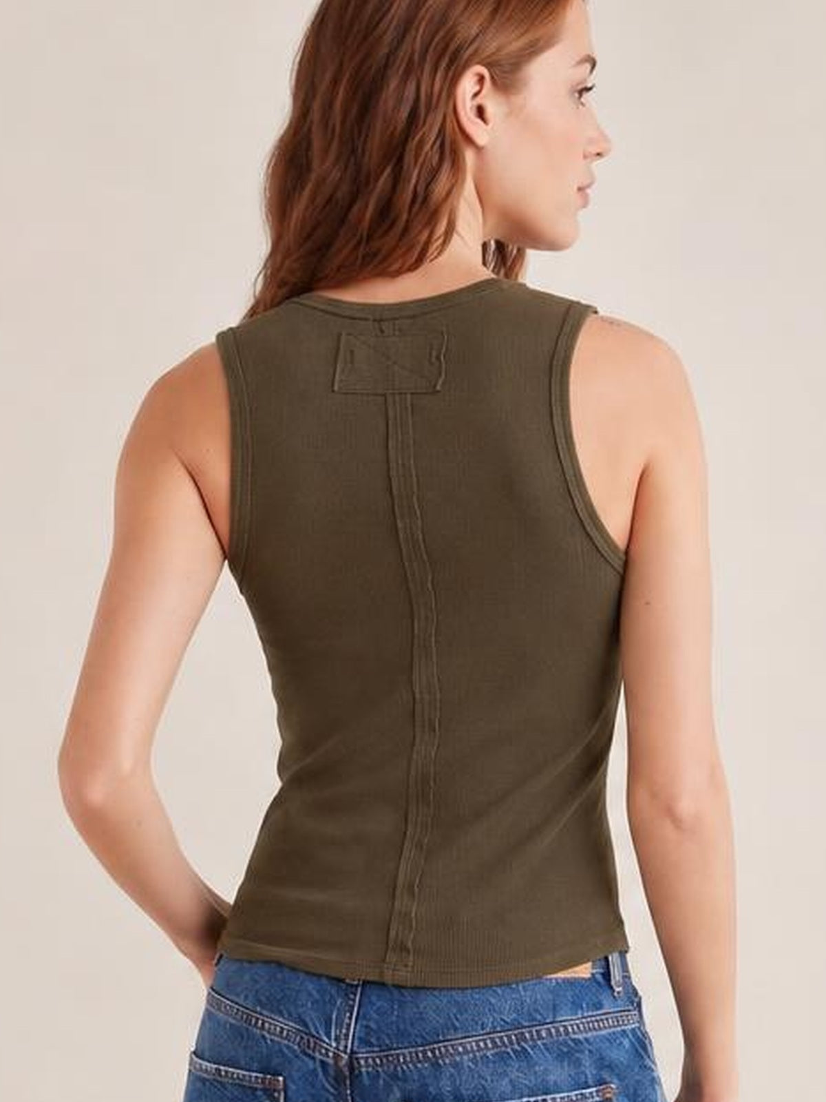 Model shown from the back wearing an olive-brown V-neck wide strap tank with a fitted silhouette, bound armholes, and a center-back seam.