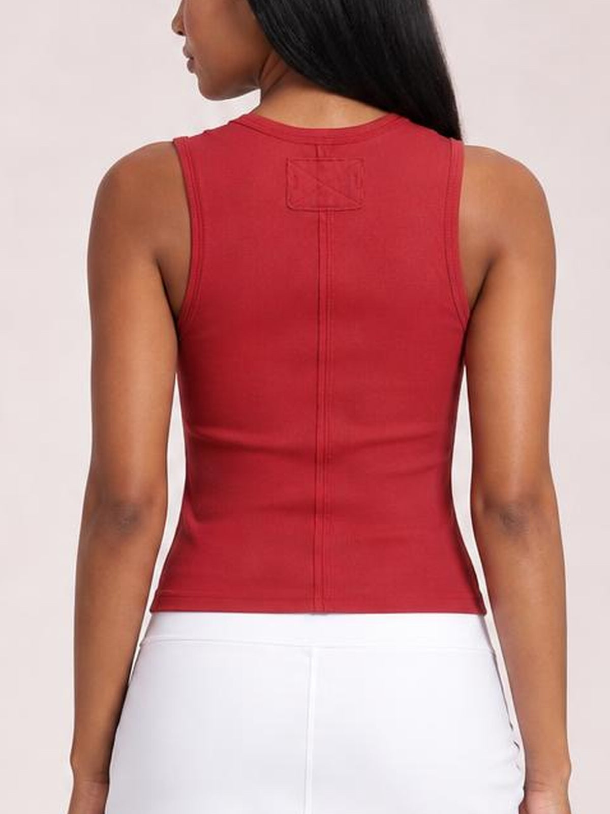 Model shown from the back in a red wide-strap tank with a fitted silhouette, bound armholes, and a central vertical seam.