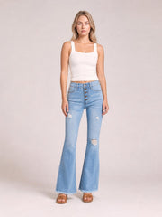 Model wears light-wash MIU Jess button flare jeans with an ultra-high rise, five-button fly, distressed knees, fitted hips, and frayed hems.