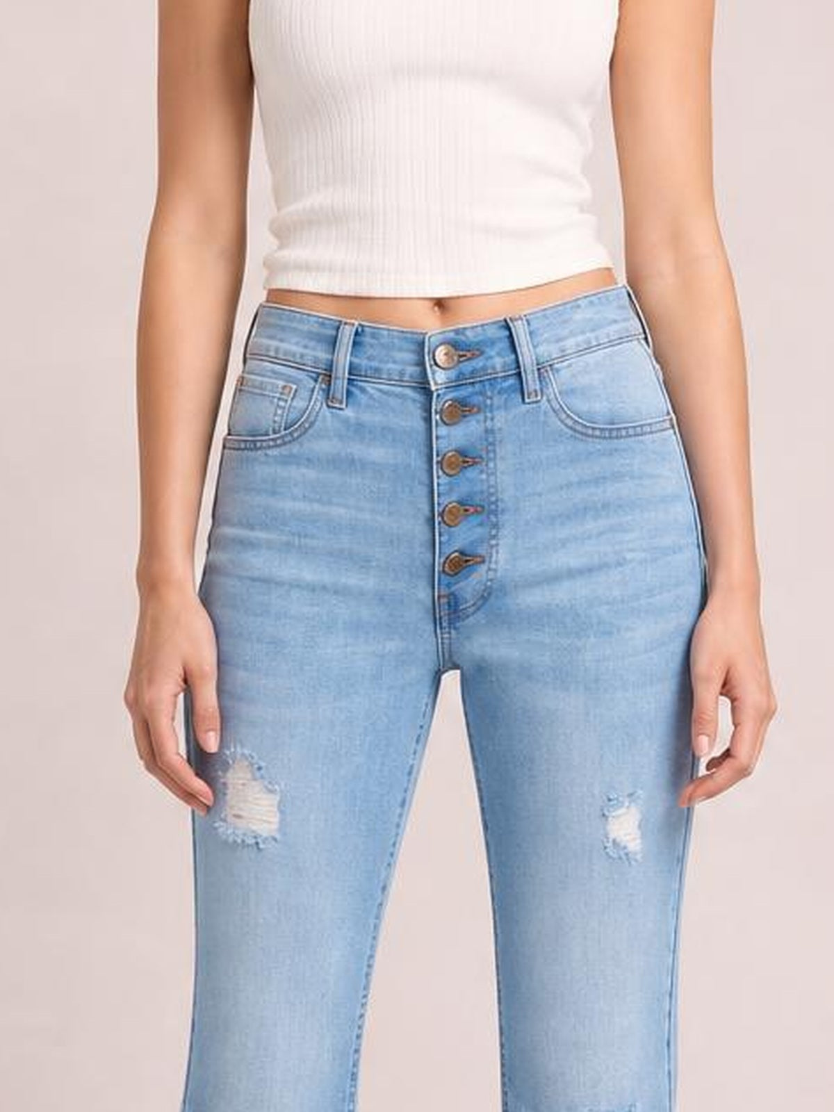 A model wears light blue MIU Jess ultra-high-rise flare jeans with a fitted silhouette, five-button fly, front pockets, and distressed patches.