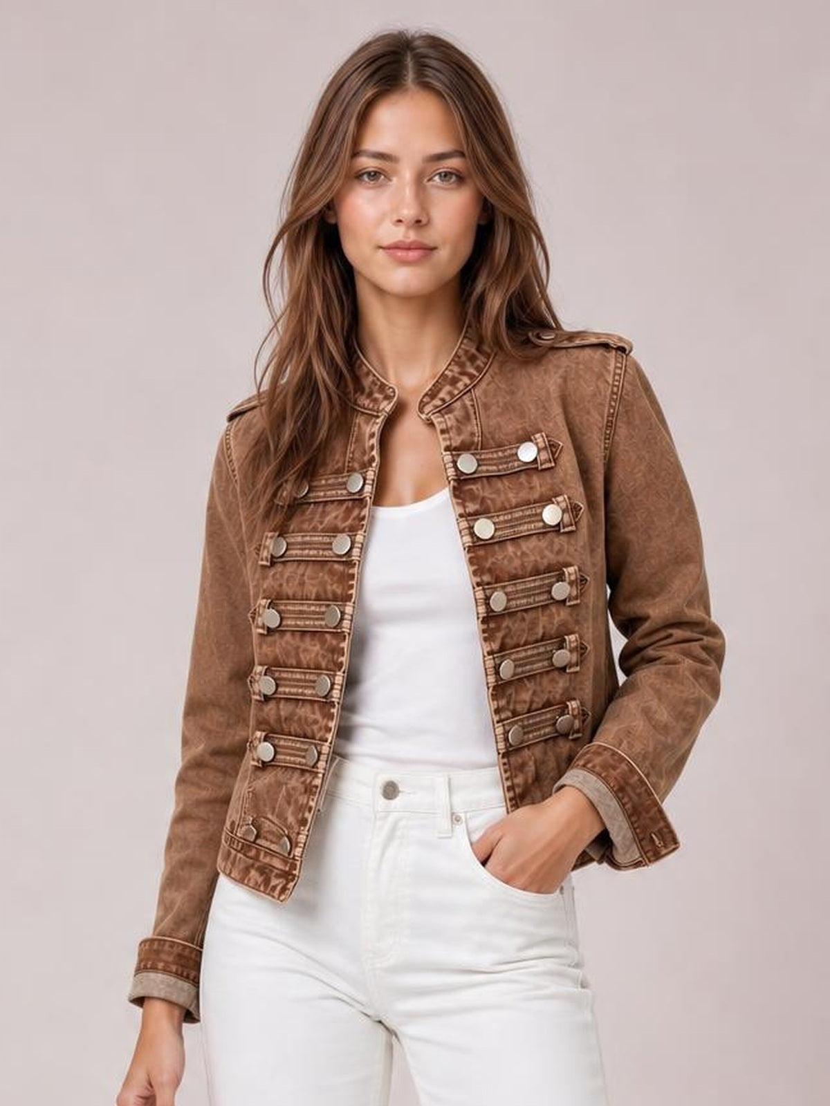 Model wears a brown washed denim jacket with an open front, stand collar, long sleeves, tailored silhouette, and rows of decorative buttoned straps.