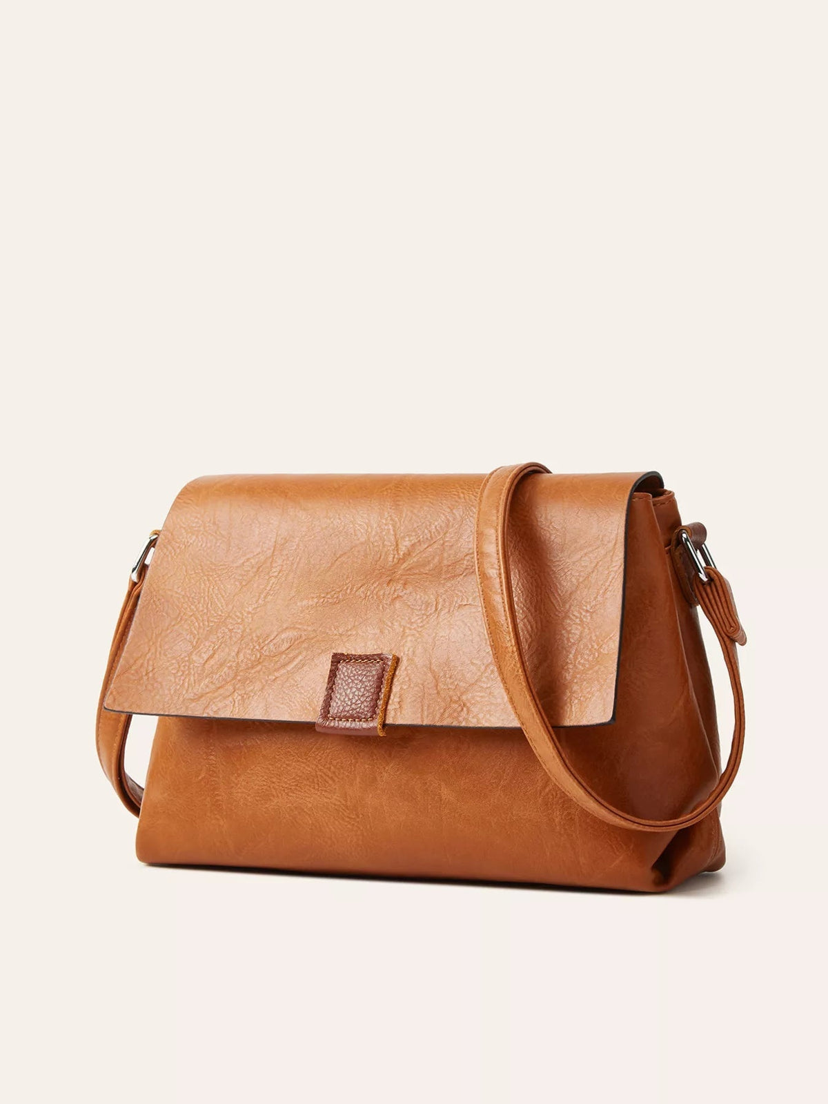 Medium vintage-style tan PU leather crossbody bag with a structured silhouette, flap closure, stitched tab detail, and long shoulder strap.