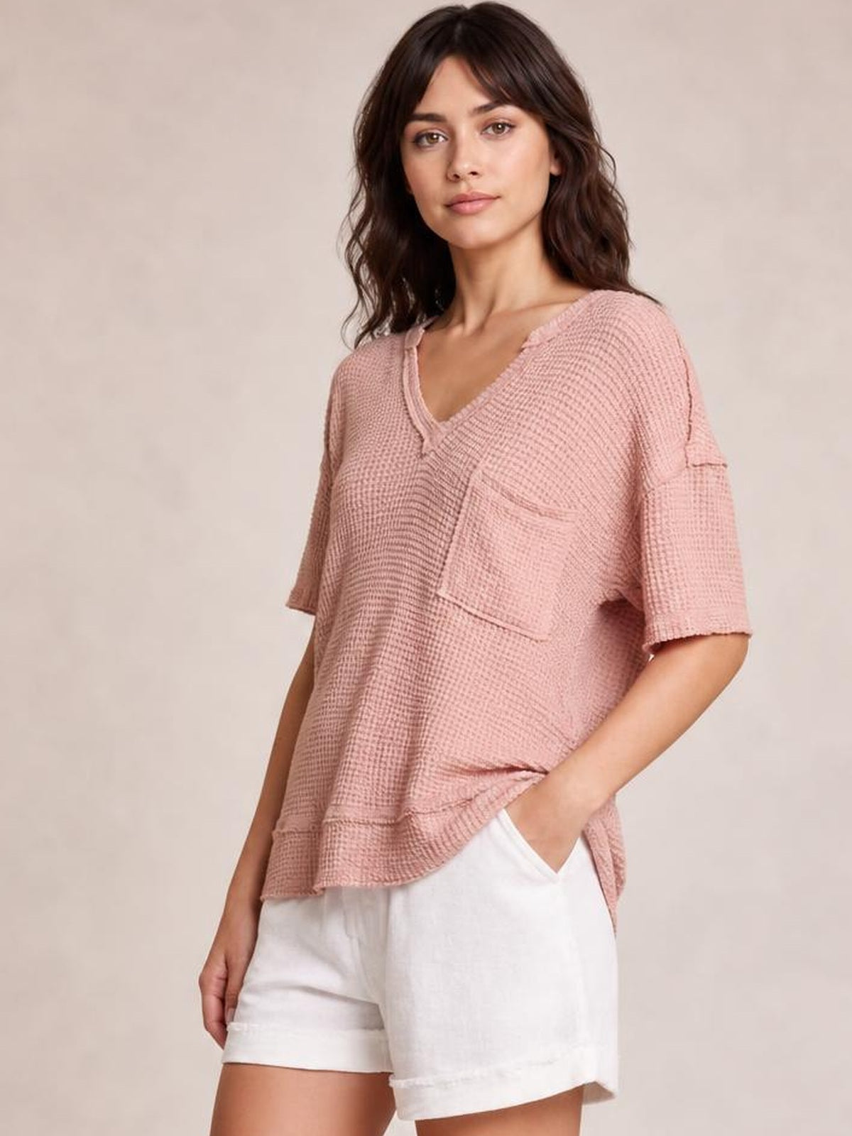 Model wears a blush pink waffle-knit T-shirt with a notched neckline, relaxed silhouette, half sleeves, and a large chest pocket.