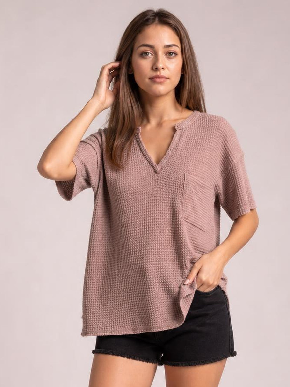 A model poses in a mauve waffle-knit T-shirt with a notched neckline, half sleeves, relaxed straight silhouette, and visible chest pocket.