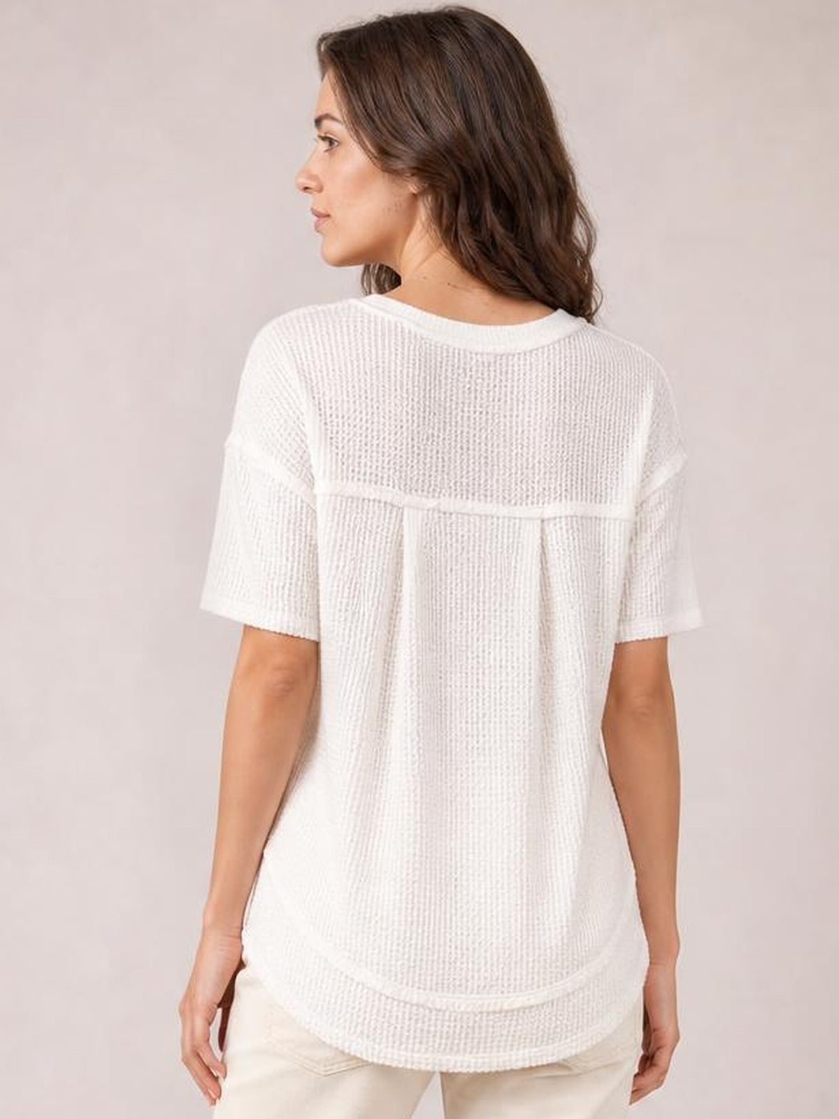 Model shown from behind wears a white waffle-knit half-sleeve T-shirt with a relaxed silhouette, rounded hem, and visible back yoke seam.
