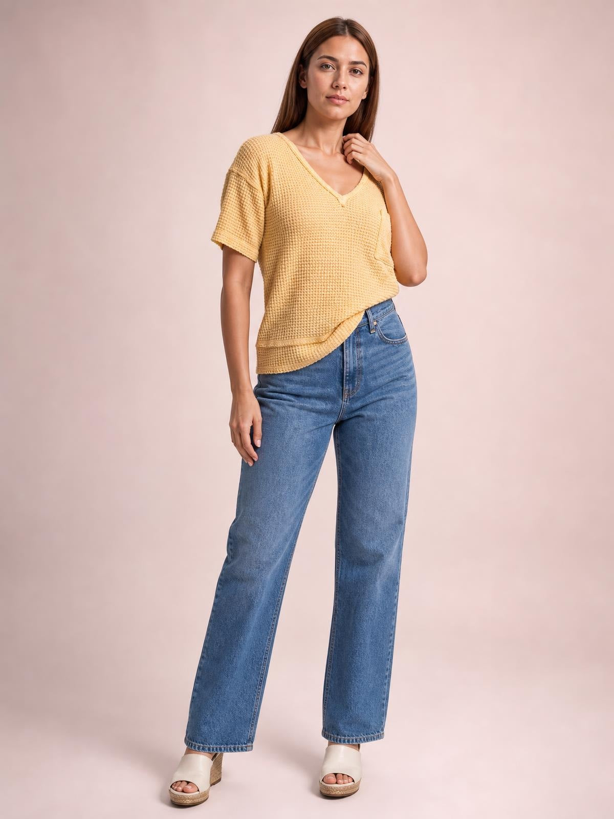 Model wearing a mustard waffle-knit T-shirt with a notched neckline, half sleeves, relaxed silhouette, curved hem, and side pocket, posing with one hand near the collar.