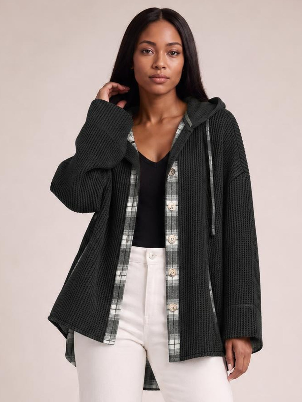 A model poses in a relaxed black waffle-knit plaid patchwork hooded shacket with an oversized silhouette, long sleeves, and button-front construction.