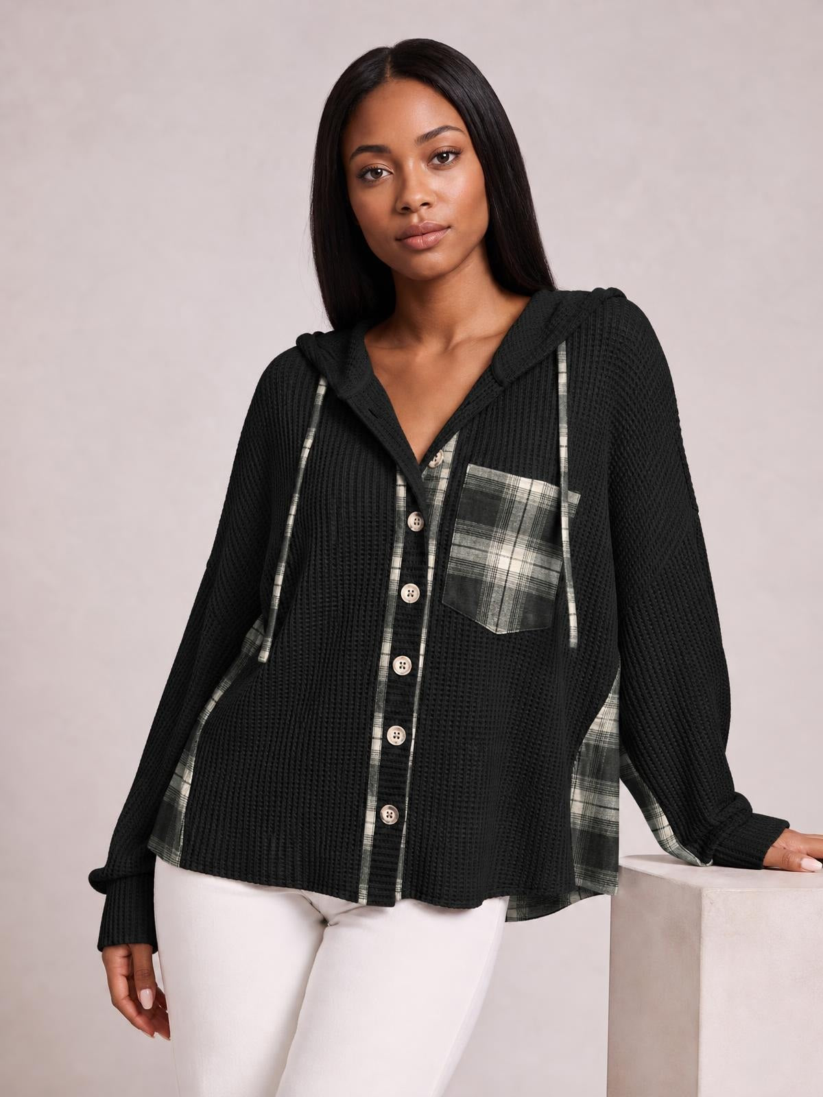 Model poses in a black waffle-knit plaid patchwork hooded shacket with drawstring ties, button front, chest pocket, long sleeves, and a relaxed silhouette.