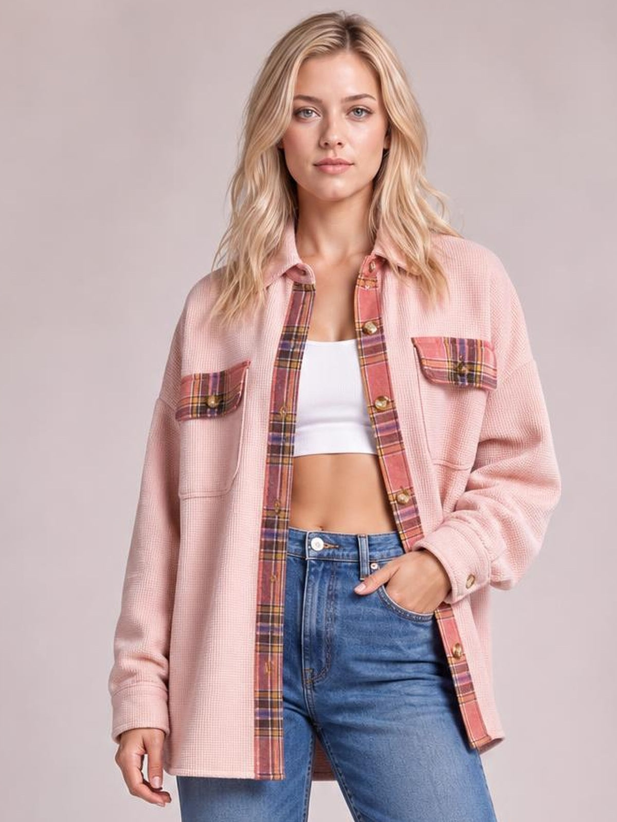 A model stands in a relaxed pink waffle-knit plaid patchwork shacket with long sleeves, button front, chest pockets, and a straight silhouette.