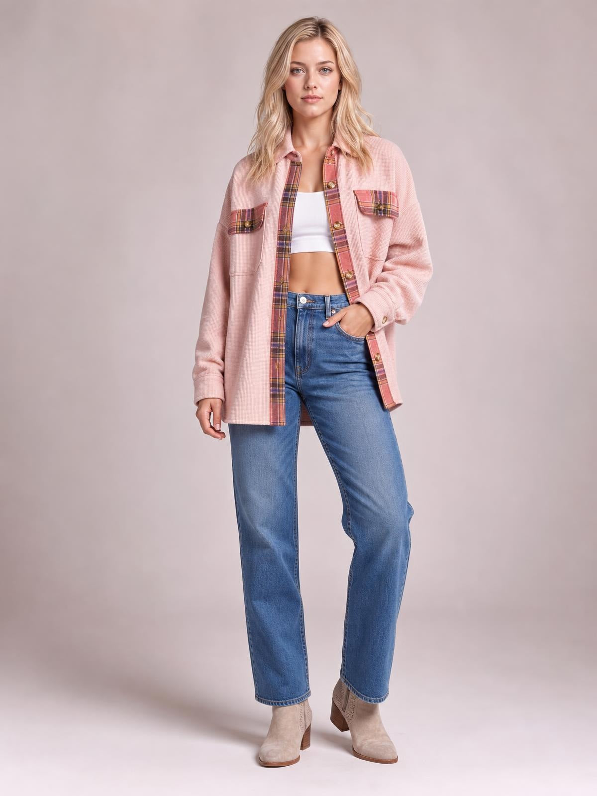 Model wears a relaxed pink waffle knit shacket with plaid patchwork trim, button front, chest pockets, and one hand tucked into a pocket.