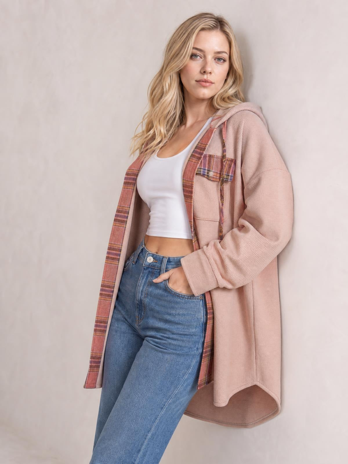 A model poses in a dusty pink waffle-knit hooded shacket with plaid patchwork trim, open front, long relaxed silhouette, and oversized sleeves.