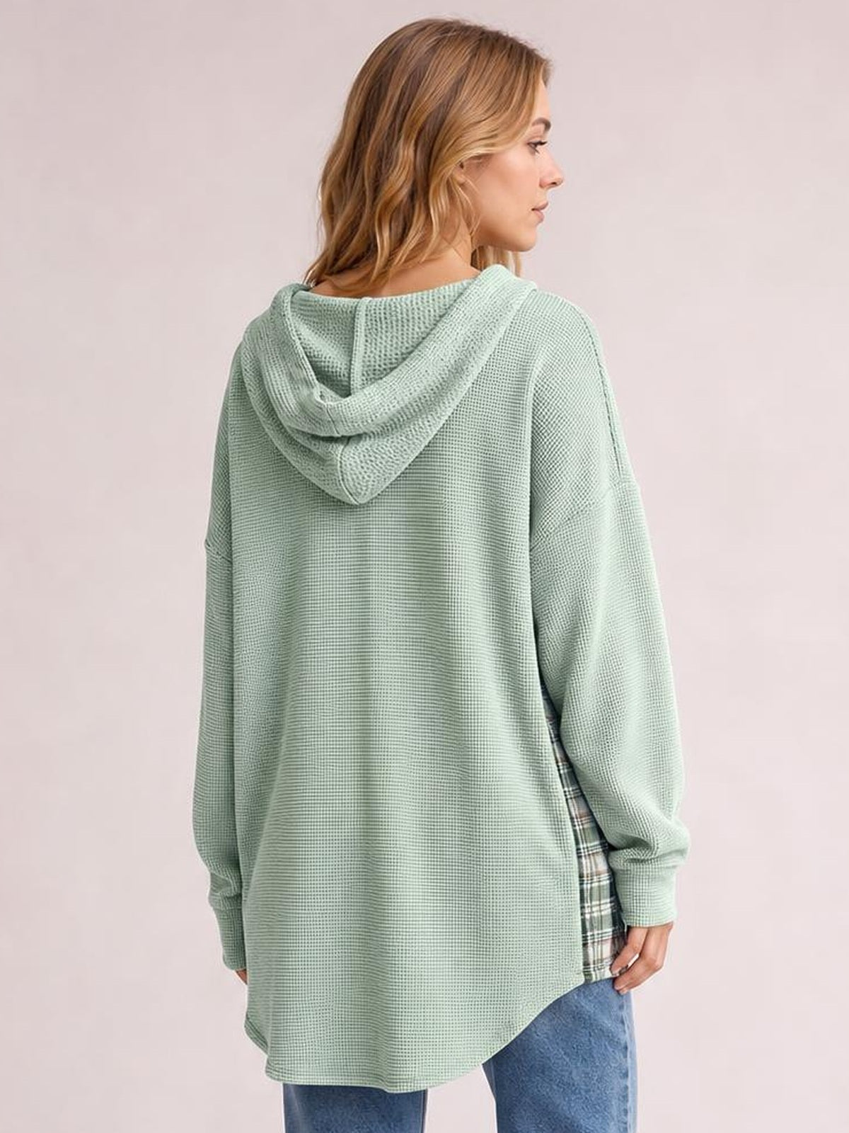 Model shown from the back in a relaxed mint green waffle knit hooded shacket with long sleeves, an oversized silhouette, and plaid patchwork side panel.