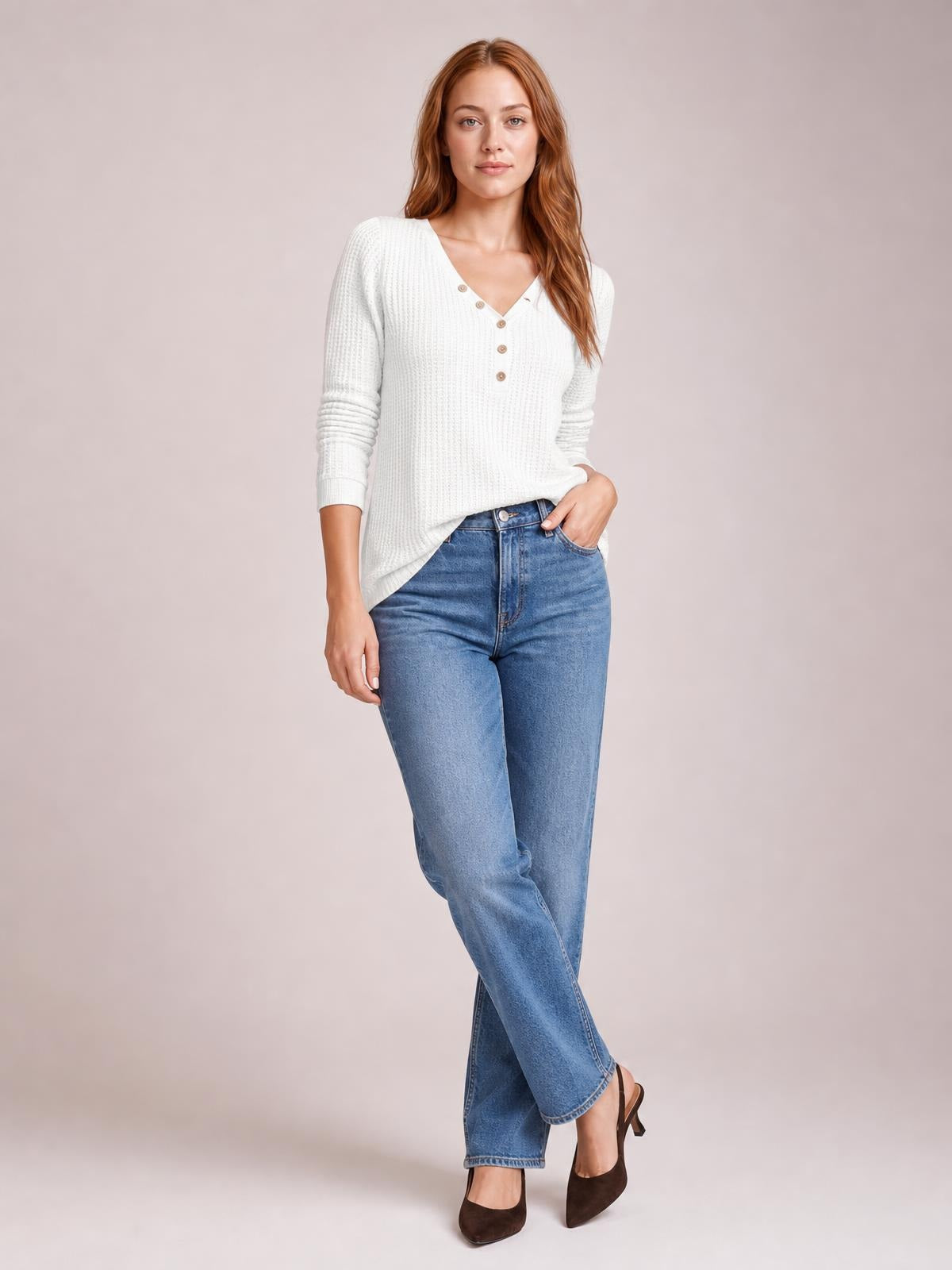 Model wears a white waffle-knit V-neck long sleeve top with button details and a relaxed silhouette, posing with one hand in her jeans pocket.