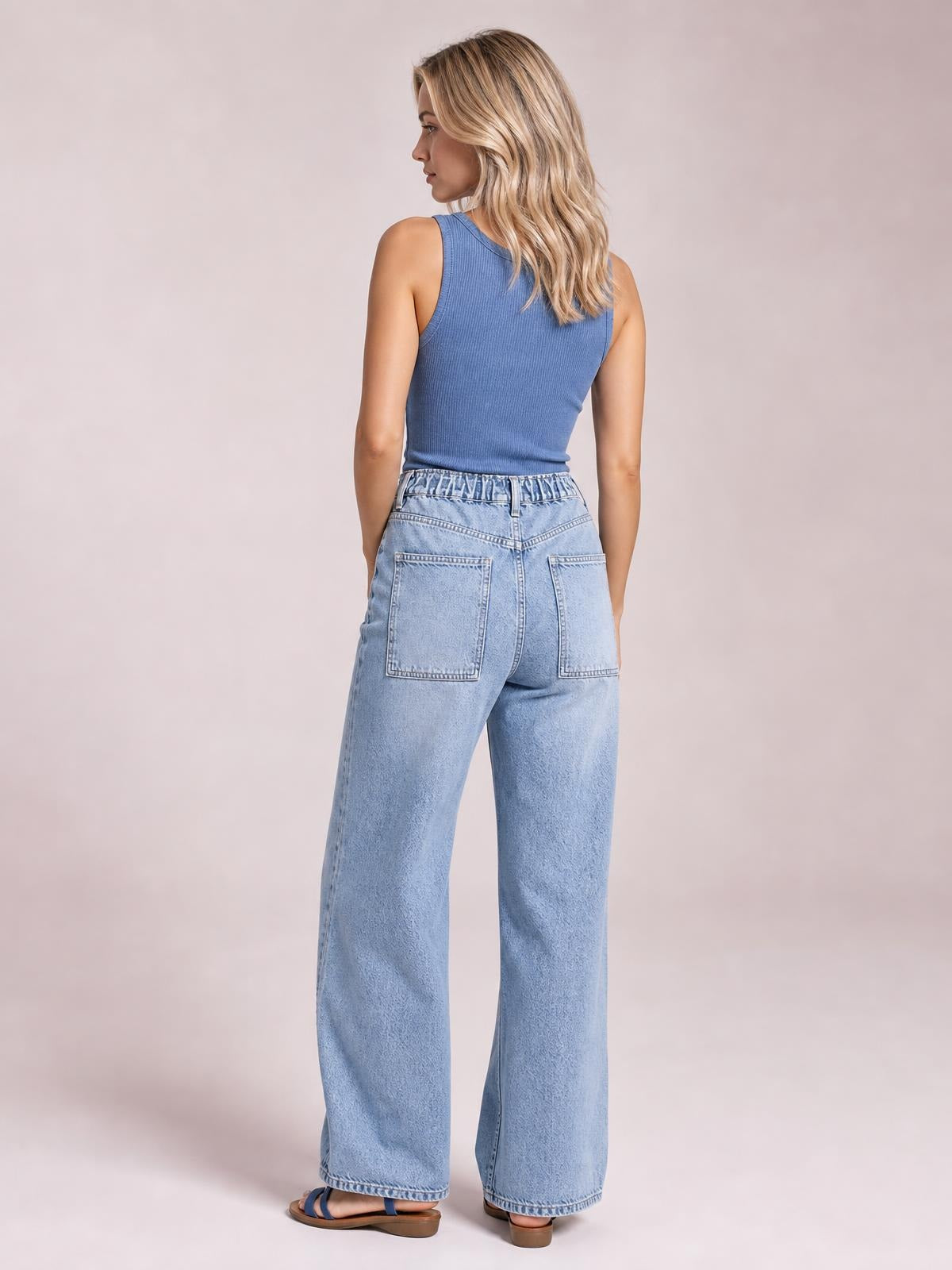 Model shown from behind wearing light-wash wide-leg cargo jeans with an elasticized waist, belt loops, stitched back patch pockets, and full-length hems.