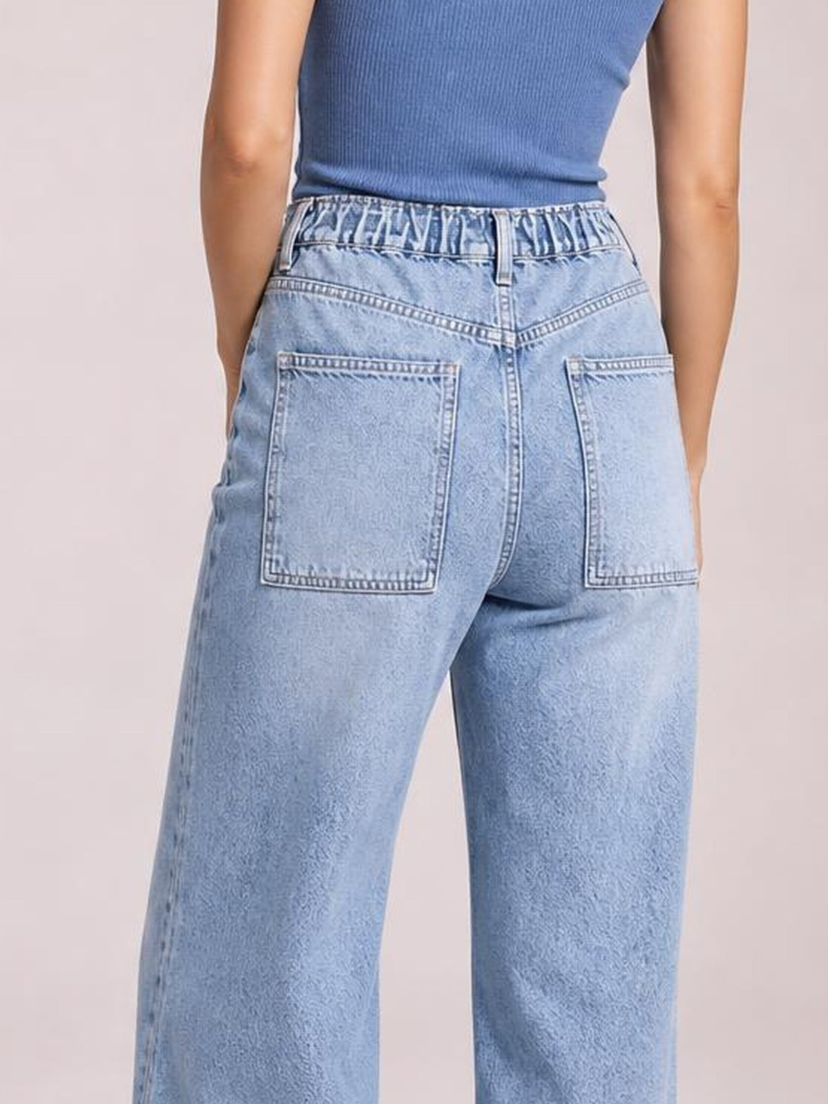 Model shown from behind wearing light-wash wide-leg cargo jeans with a high-rise tied waistband, belt loops, and large back patch pockets.