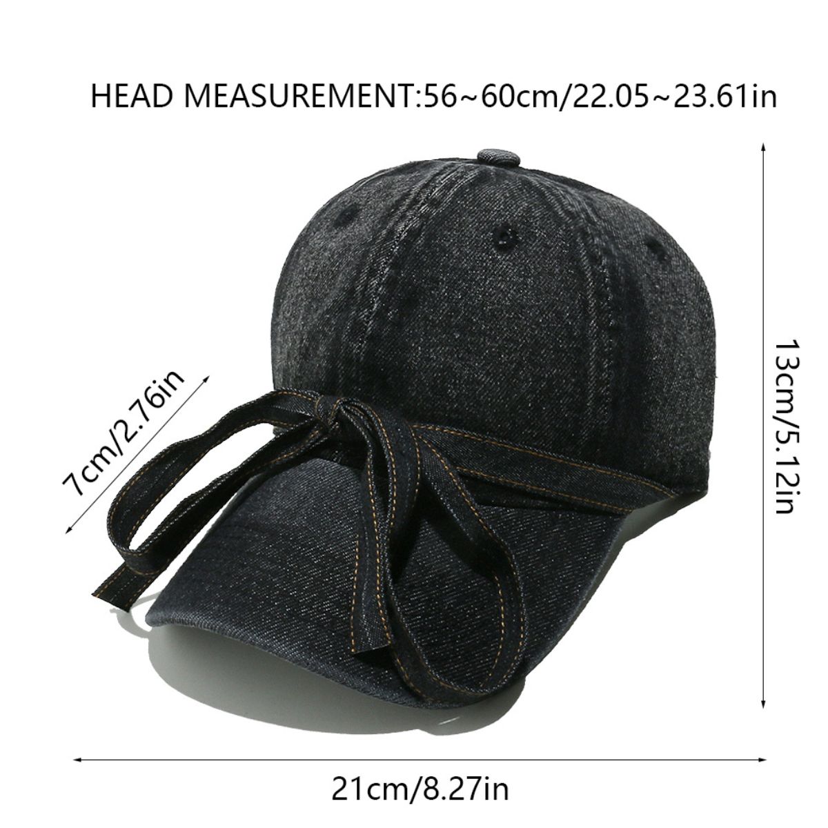 Washed dark denim baseball cap with a curved brim, seamed crown, top button, ventilation eyelets, and an oversized front bow with trailing ends.