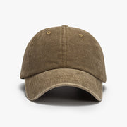 Washed brown cotton baseball cap with a relaxed rounded crown, curved brim, visible panel seams, ventilation eyelets, and a top button.