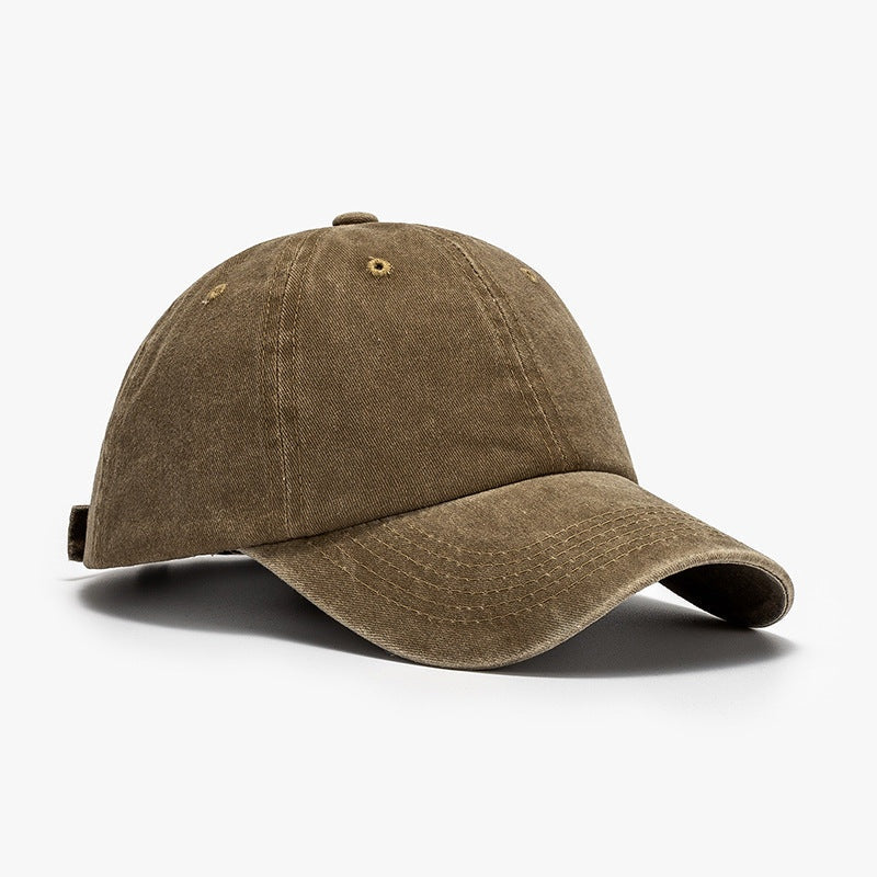 Washed brown cotton baseball cap with a relaxed rounded crown, curved brim, visible panel seams, stitched detailing, ventilation eyelets, and an adjustable back strap.