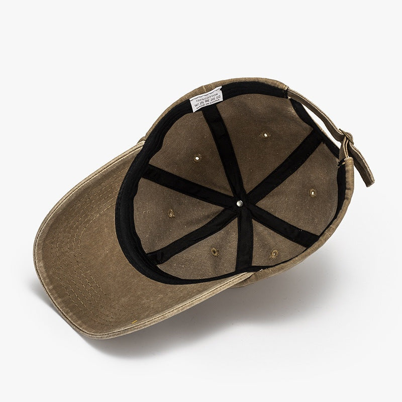 Washed cotton baseball cap in olive brown with a curved, neatly stitched brim, visible panel seams, ventilation eyelets, and an adjustable back strap.