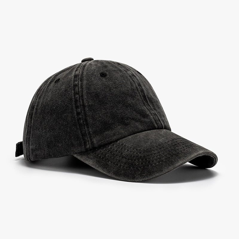 Washed black cotton baseball cap with a relaxed rounded crown, visible panel seams, crown button, ventilation eyelets, and a distinctly curved brim.