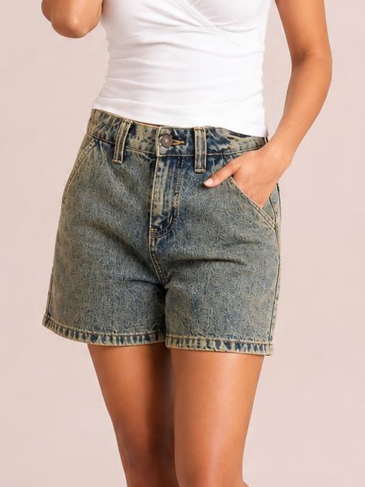 Model wearing washed blue high-rise denim shorts with a straight relaxed silhouette, belt loops, button fly, front pockets, and neatly finished hems.