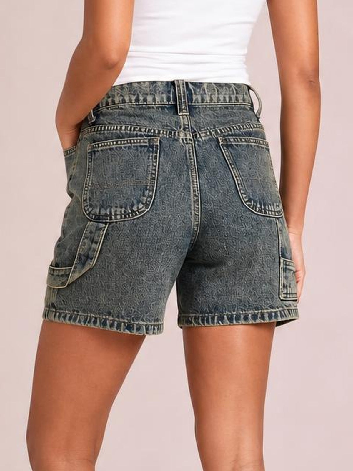 Model shown from behind wearing washed high-rise denim shorts with a relaxed silhouette, multiple utility pockets, belt loops, and cuffed hems.