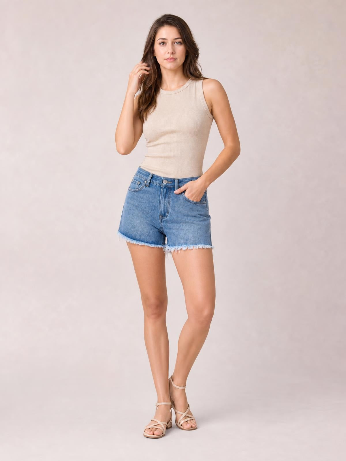 Model poses in light blue washed raw hem denim shorts with front pockets, belt loops, zip fly, and a relaxed mid-rise silhouette.