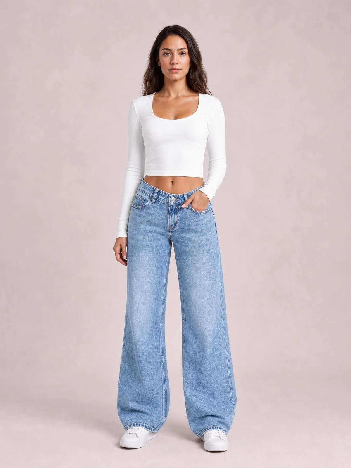 Model wearing light blue washed wide leg jeans with front pockets, belt loops, button closure, and a relaxed full-length silhouette, standing with one hand in a pocket.