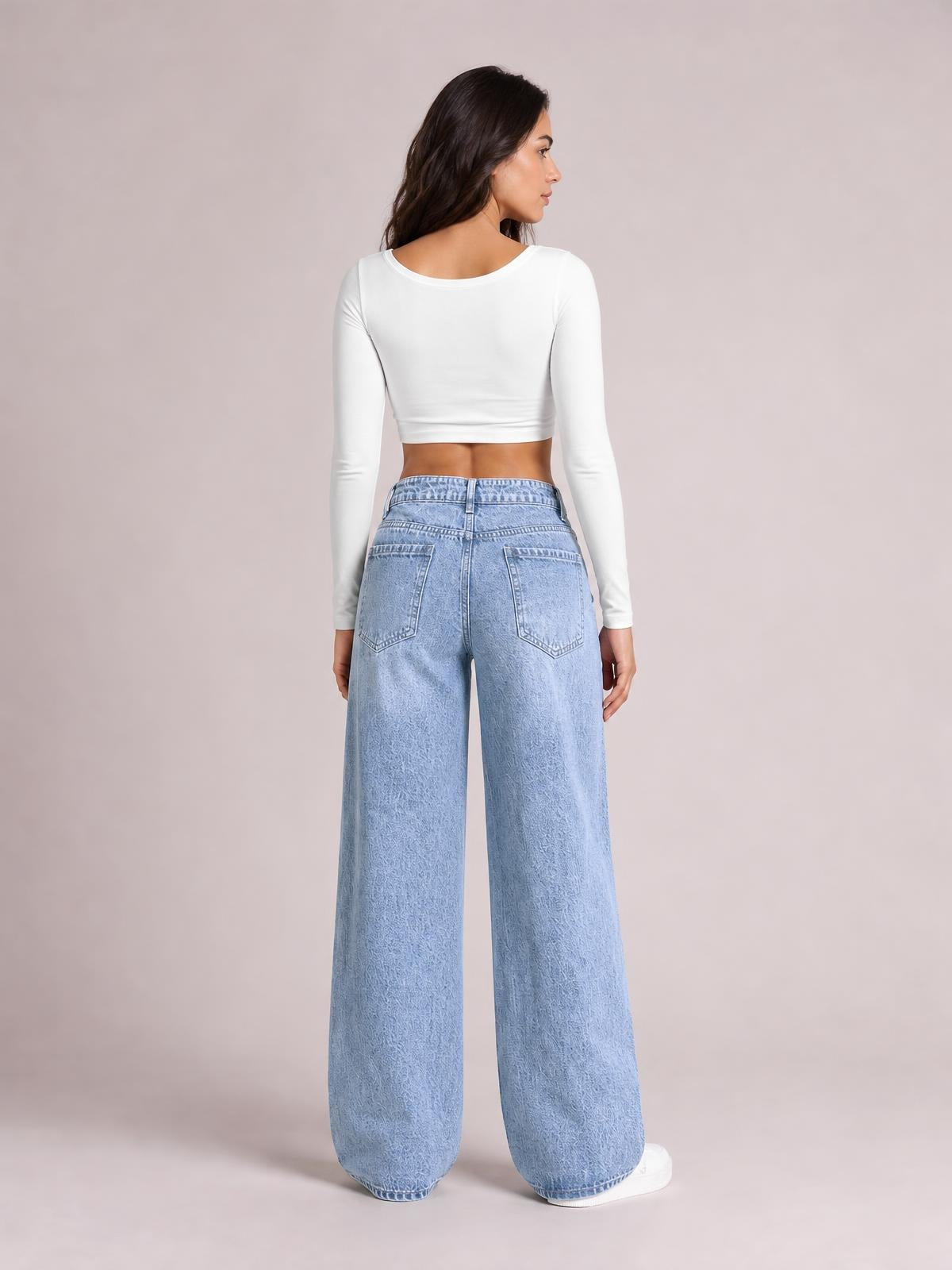 Model shown from the back wearing washed light blue wide leg jeans with a high waist, belt loops, rear patch pockets, and full-length relaxed legs.