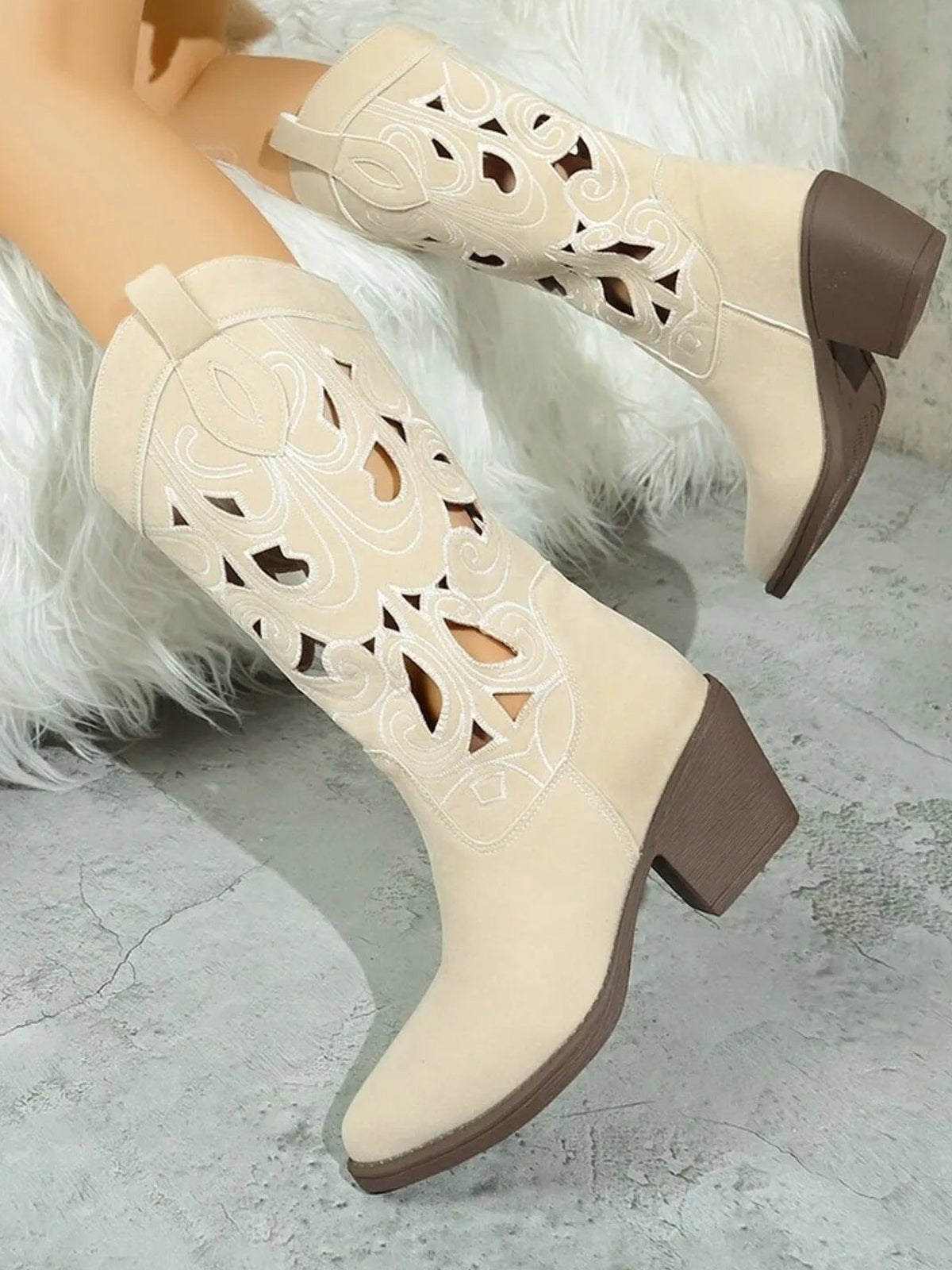 Cream Western cutout pattern boots feature ornate scrollwork, pointed toes, sleek silhouettes, and contrasting brown mid-height block heels.