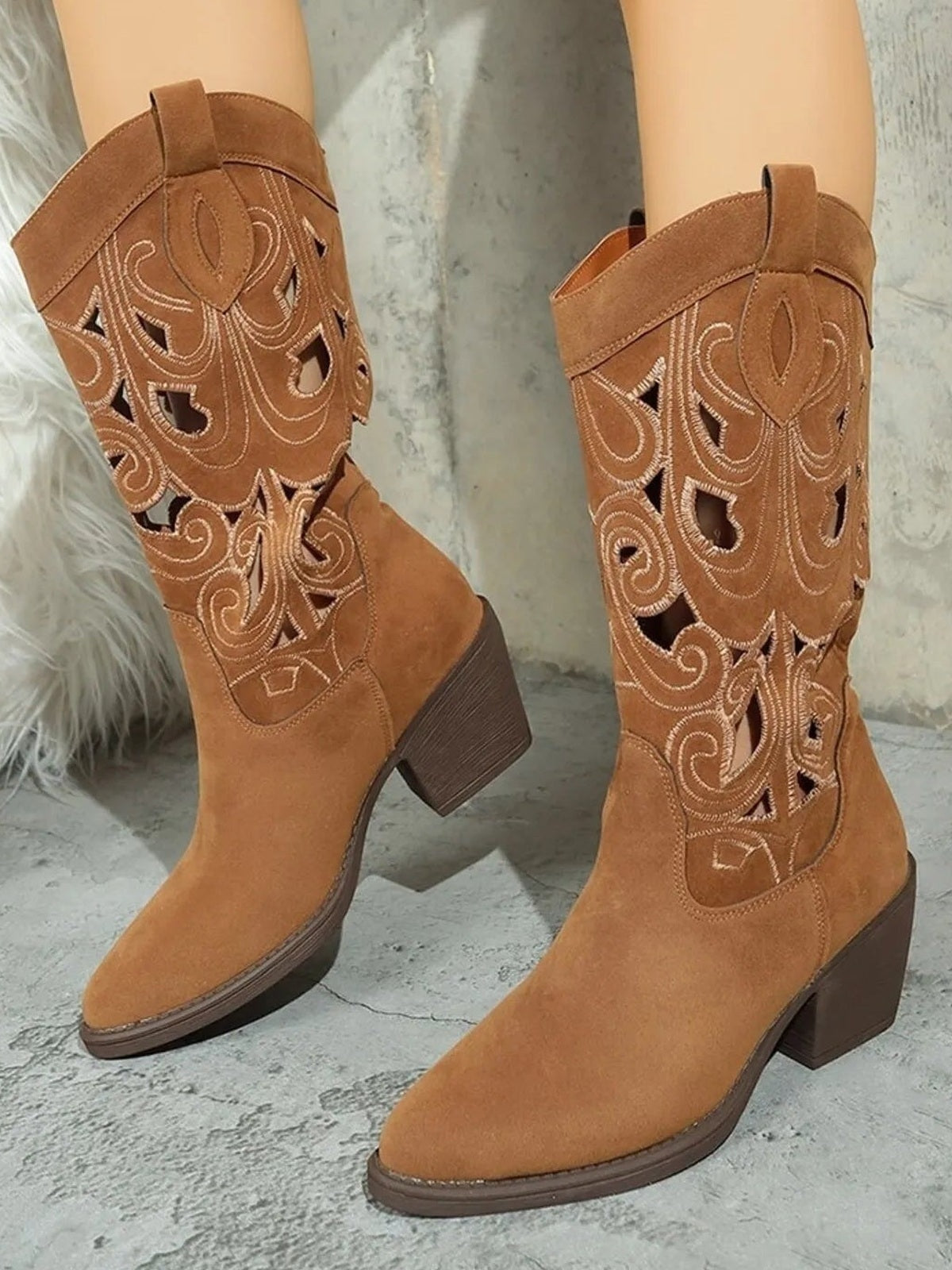 Tan Western boots with pointed toes, mid block heels, and embroidered cutout patterns across the shafts, featuring contrasting dark soles and pull tabs.