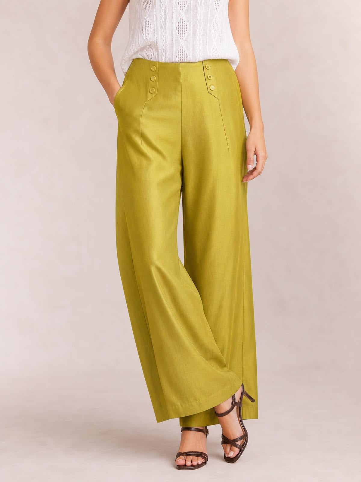 Model poses in olive-green wide-leg pants with decorative buttons, angled pocket seams, a high waist, and long flowing legs.