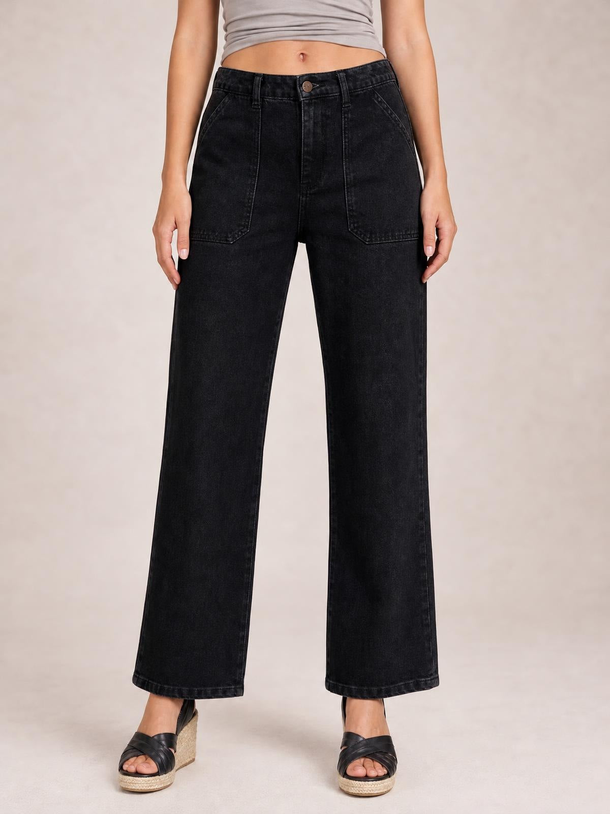 Model stands facing forward in black wide-leg jeans with contrast stitching, a buttoned waistband, belt loops, and large front patch pockets.