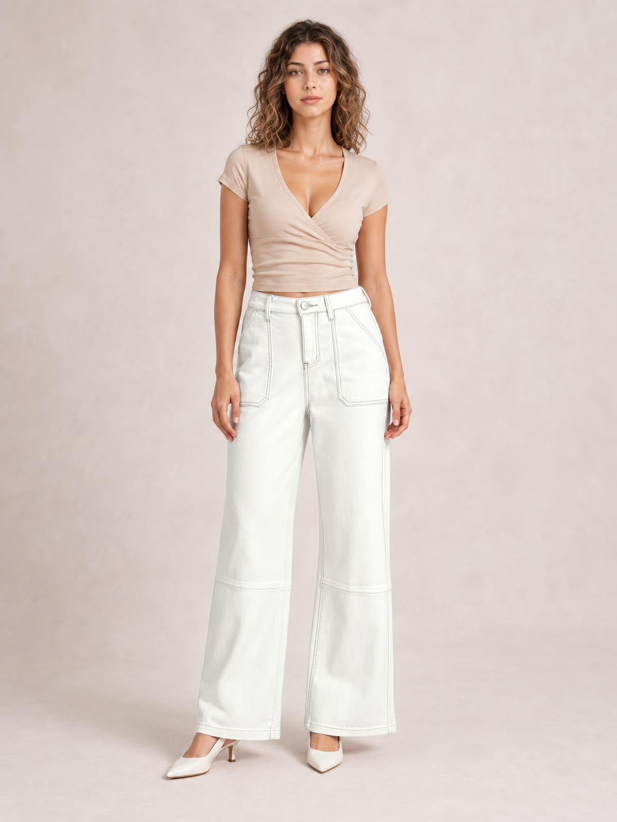 Model standing in white wide-leg jeans with contrast stitching, a high waist, front patch pockets, belt loops, and structured seamed legs.